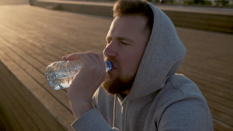 man drinking water at sunset on a pier