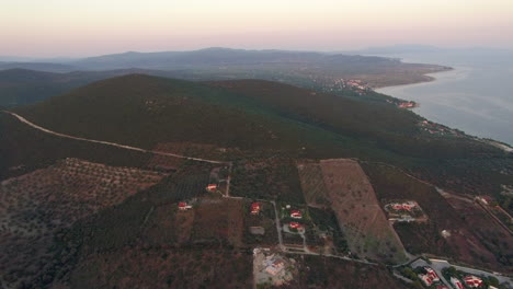 Flying-over-green-landscape-with-plains-and-hills-in-coastal-town-Greece