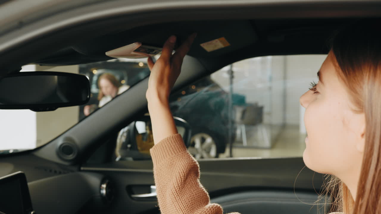 mujer examinando las características interiores de un coche en una sala de exposiciones