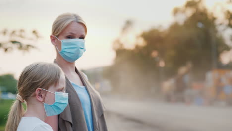 A-Woman-With-A-Child-In-Protective-Masks-Are-Standing-Near-A-Dirty-Dusty-Road-In-The-City