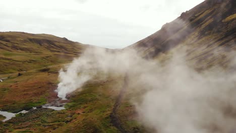 Drone-flying-through-the-steam-of-a-geothermal-hot-spring-in-Hveragerði,-Iceland