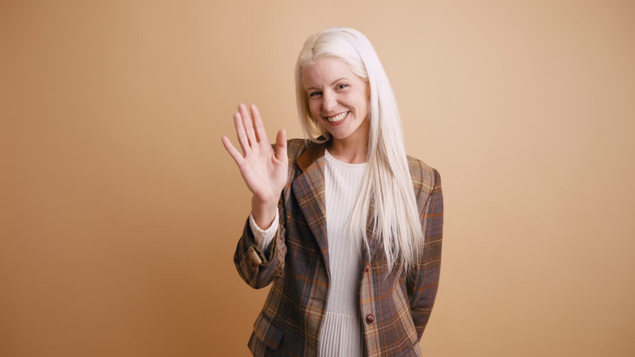 Donna bionda felice saluta e sorride alla telecamera