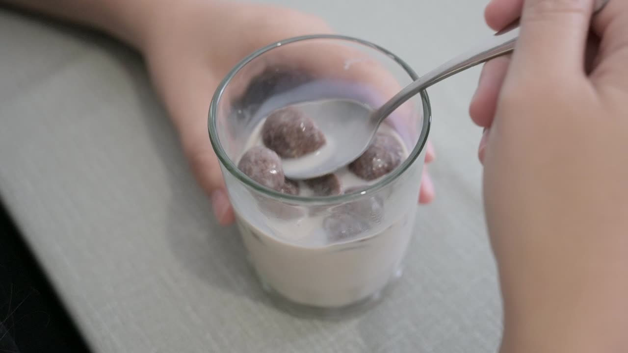 persona comiendo cereal de chocolate en un vaso de leche