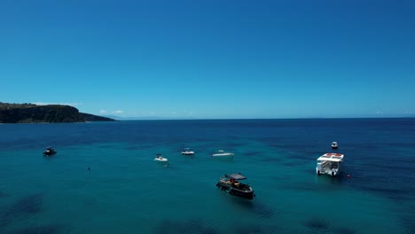 tourist motorboats and sailboats floating in the blue ionian sea bay near the pier in himara's rocky coastal beauty