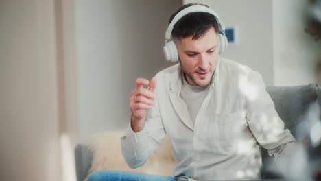 man puts on headphones and starts remote work on laptop