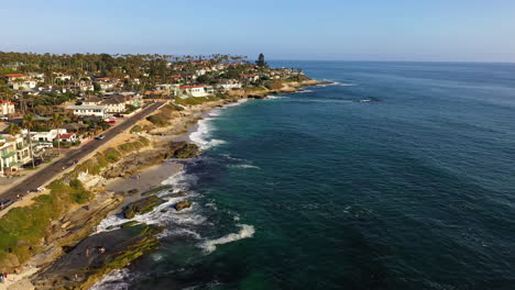 ocean waves crashing on windansea beach with waterfront buildings in la jolla, california, usa