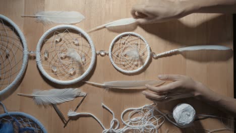 female hands creating dream catcher closeup, vertical angle