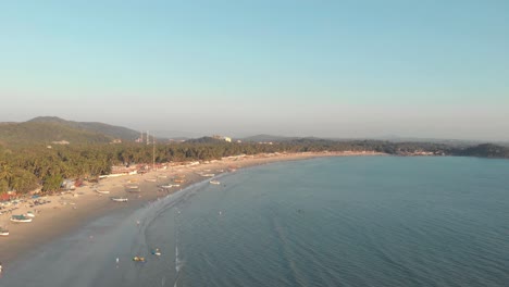 Costa-Que-Se-Extiende-Por-El-Horizonte-Con-Barcos-De-Pesca-Amarrados-En-Las-Arenas-Doradas-Cerca-De-La-Costa-En-La-Playa-De-Palolem,-En-Goa,-India---Toma-Panorámica-Aérea