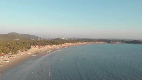 coastline stretching across the horizon with fishing boats moored on the golden sands near the coast in palolem beach, in goa, india - aerial panoramic shot