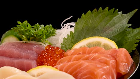 a vibrant assortment of salmon, tuna, scallop, and roe sashimi is presented on a platter with lemon, shiso leaves, and garnish, under studio lighting with smooth rotational camera movement