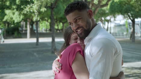 una feliz pareja multirracial abrazándose al aire libre.
