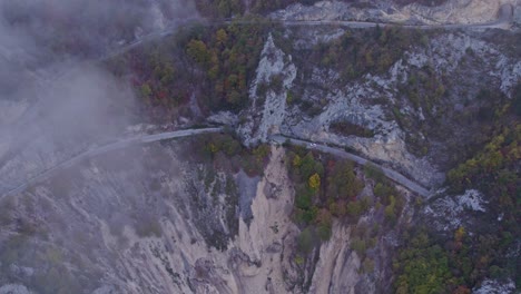 Camino-En-El-Cañón-Del-Lago-Piva-Montenegro-Con-Nubes-Bajas-Durante-El-Otoño,-Antena