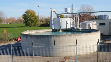 large circular open-air industrial tank with running water tap in slow motion