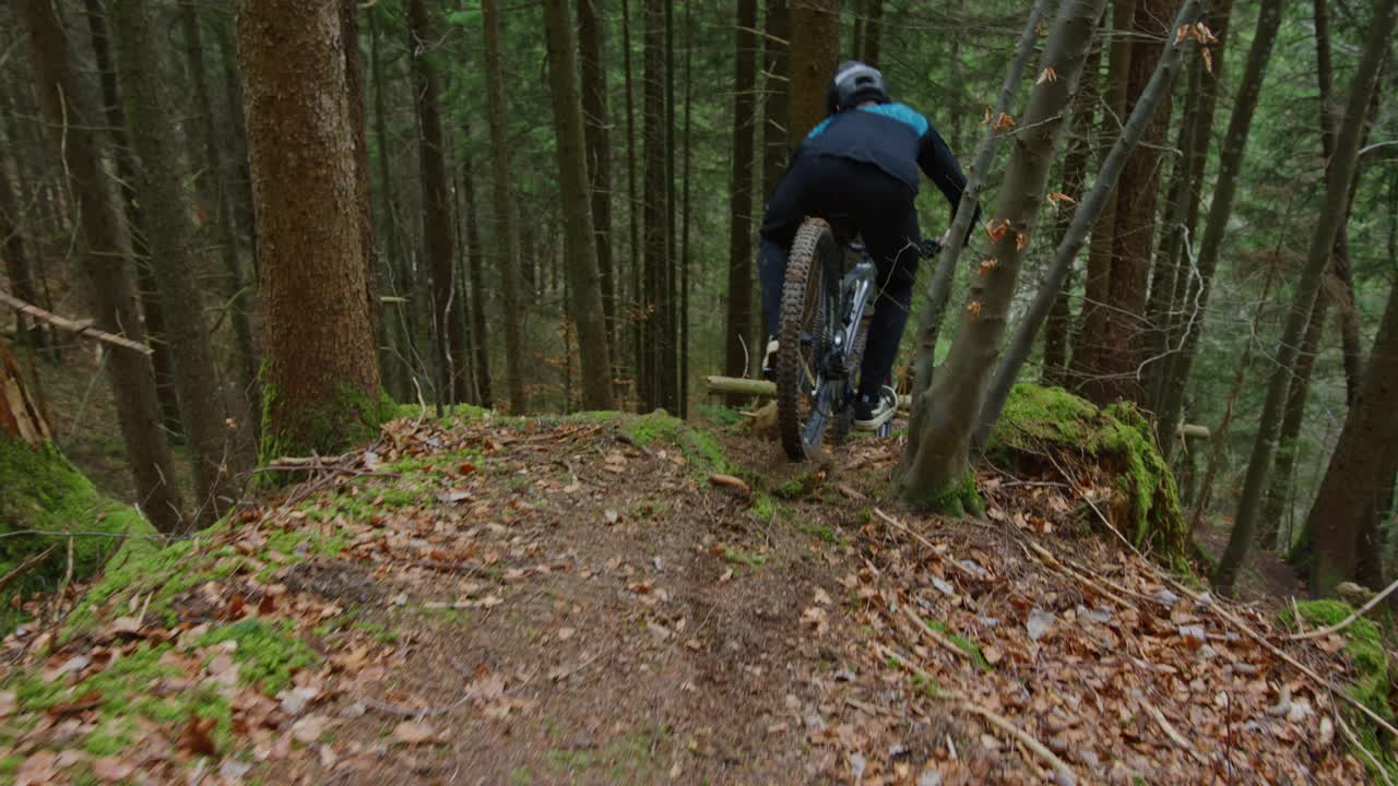un ciclista está montando una cresta técnica estrecha en el bosque