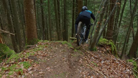 A-cyclist-is-riding-a-narrow-technical-ridge-in-the-forest