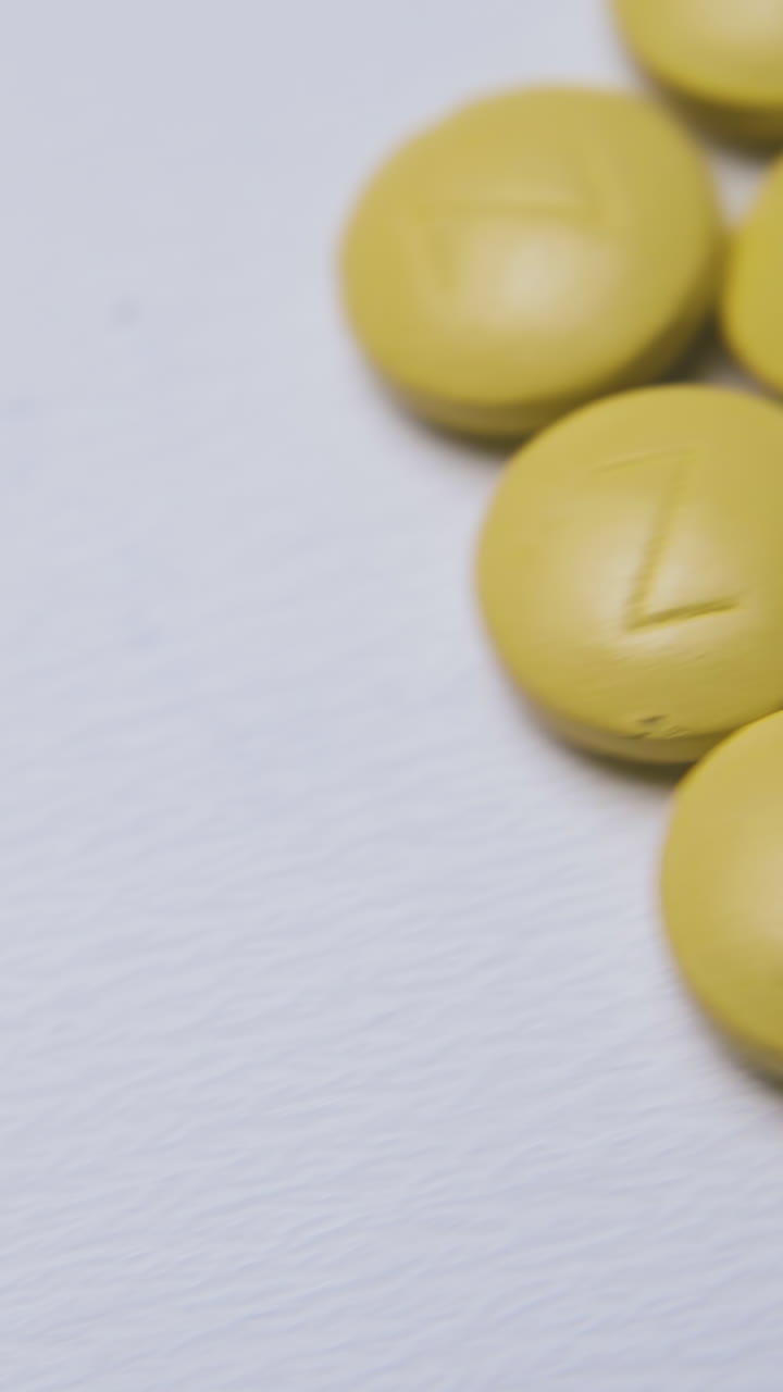 motion above piles of pills and capsules scattered on clean light background extreme close view