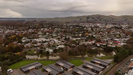 small neighborhood in new zealand during cloudy day. aerial wide shot. mountains and river flowing through city. blenheim, south island
