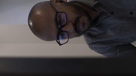 hombre calvo de oficina moderna con gafas de lectura, vista detrás del monitor