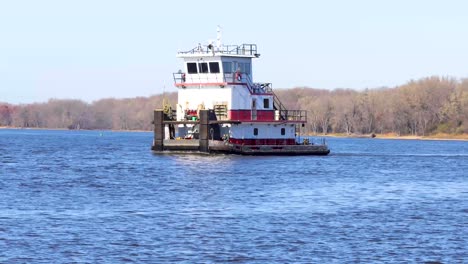 un primer plano de un remolcador de barcaza vacío moviéndose bastante rápido por el río mississippi en un día de otoño nublado