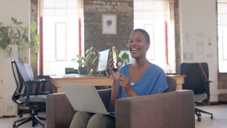 Feliz-Mujer-De-Negocios-Afroamericana-Casual-Hablando-Por-Teléfono-Inteligente-En-Una-Oficina-Creativa,-Cámara-Lenta