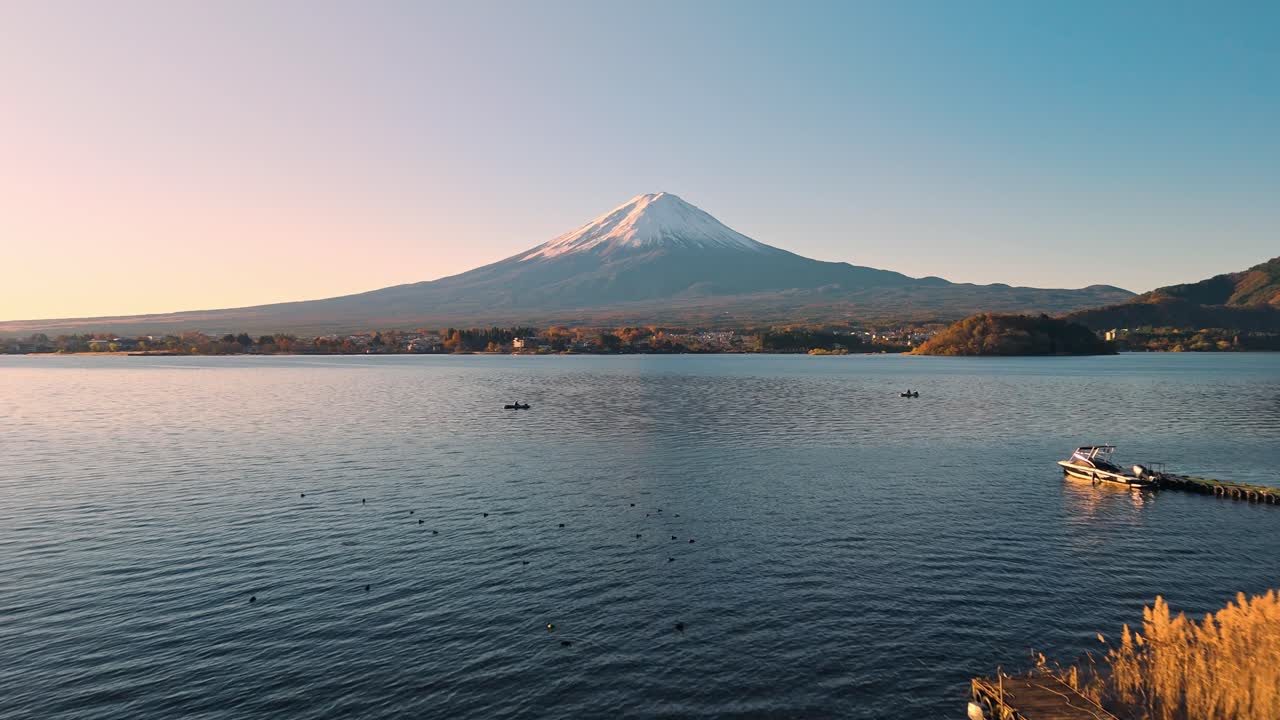 This stunning drone footage captures the serene beauty of Lake Kawaguchi at sunrise, surrounded by vibrant red autumn foliage and the majestic Mount Fuji in the background.