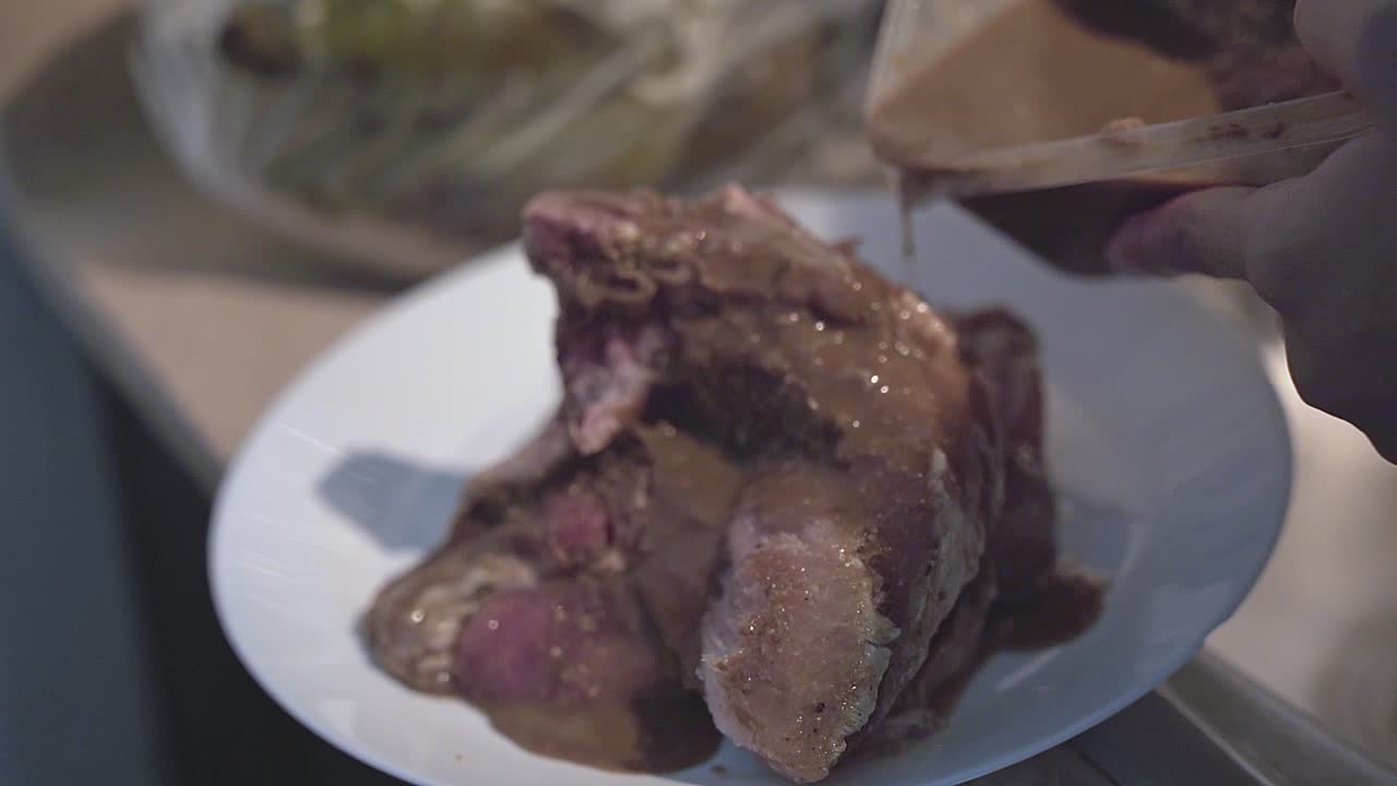 las manos vierten la salsa en la chuleta. camara lenta