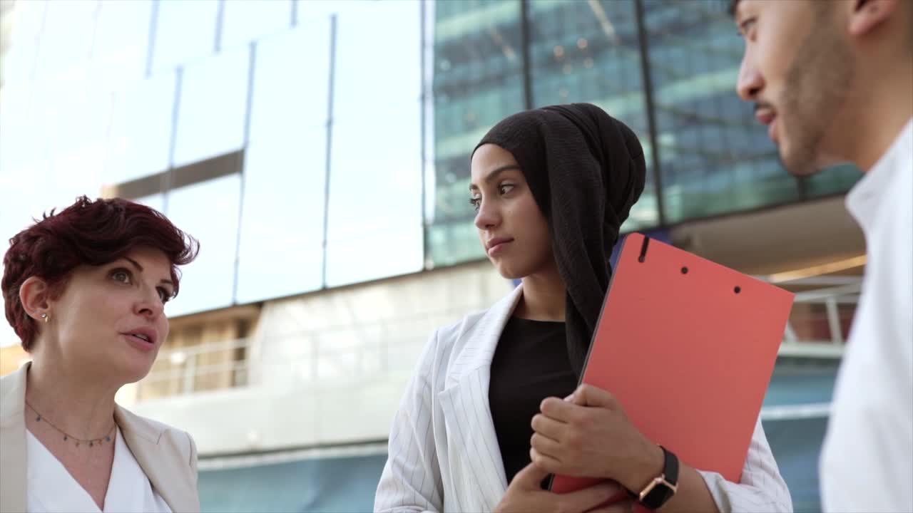 multiracial male and female coworkers talking leaving work outdoors