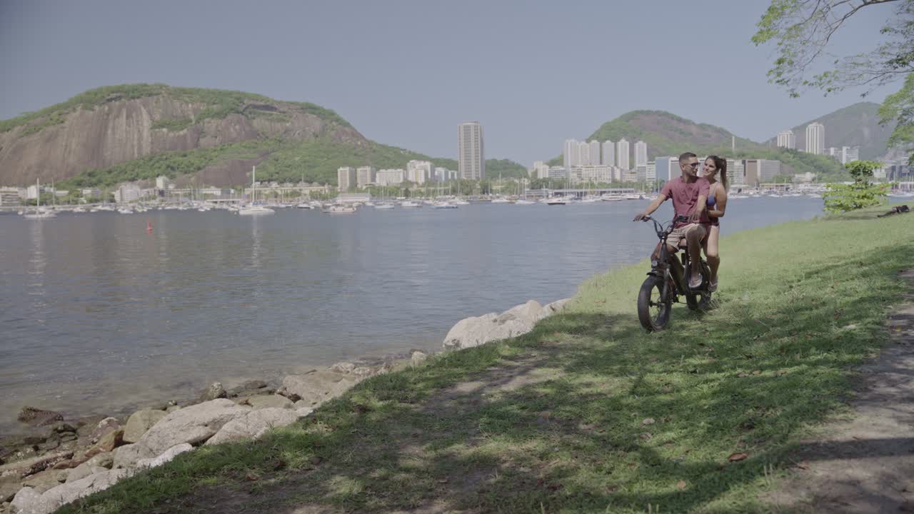 Happy Couple Enjoys an Electric Bike Ride by a Scenic Bay