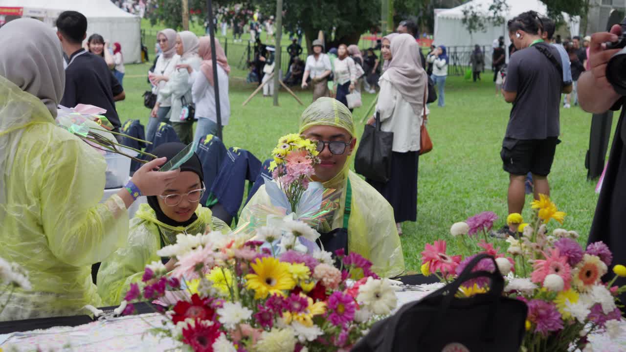 Man in raincoat creating a bouquet of flowers outdoors