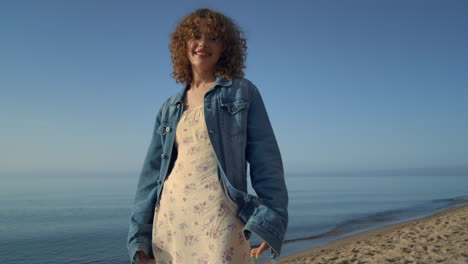 Linda-Mujer-Mirando-Cámara-Parada-En-La-Playa-De-Cerca.-Retrato-De-Niña-Sonriente.