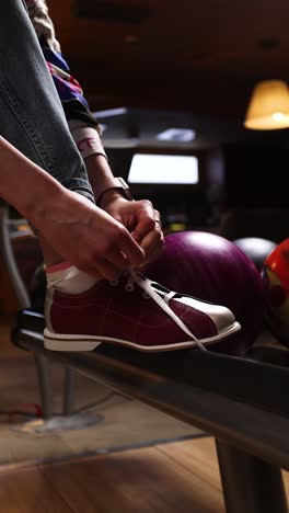 woman tying bowling shoes in alley