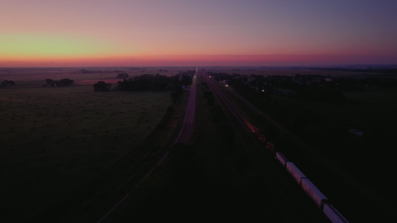 Freight Train Moving at Twilight Parallel to Highway | Supply Chain Network in Nebraska, USA