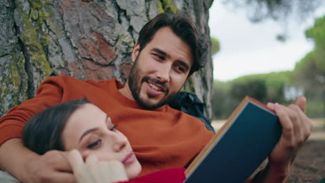 hombre leyendo libro picnic para mujer relajada de cerca. pareja romántica en el parque.