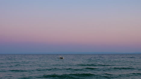 Paisaje-Acuático-Nocturno-Con-Un-Barco-Solitario-Balanceándose-Sobre-Las-Olas-Del-Mar