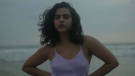 Woman-in-purple-swimsuit-enjoys-serene-beach-at-dusk,-waves-in-background,-close-up