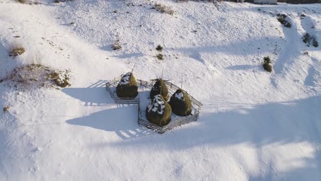 aerial orbit around traditional farmer's haystacks in romania, during winter time, at sunset