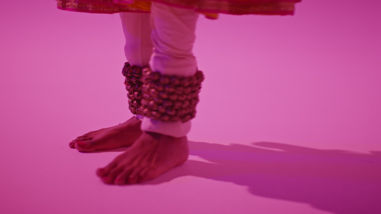 cerca de los pies y las campanas de la bailarina de kathak femenina que realiza el baile vestida con el vestido tradicional indio contra un fondo púrpura 2
