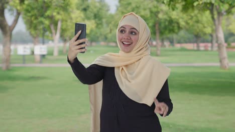 happy muslim woman clicking selfies in park