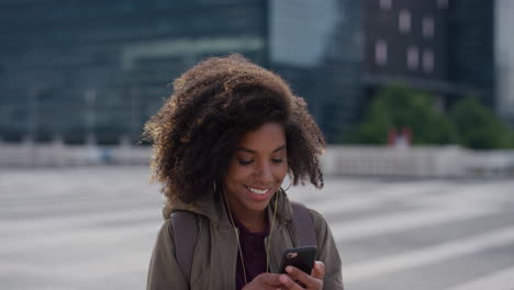 portrait young happy african american woman using smartphone taking selfie photo in city enjoying relaxed urban lifestyle wearing earphones listening to music trendy afro hairstyle