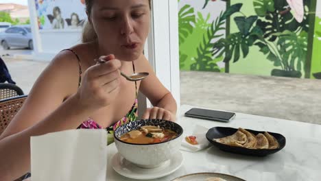 woman eating tom yum soup in a cafe