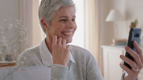 hermosa mujer madura teniendo video chat usando teléfono inteligente abuela disfrutando de la conversación mirando sorprendido compartiendo estilo de vida charlando en teléfono móvil relajándose en casa 4k