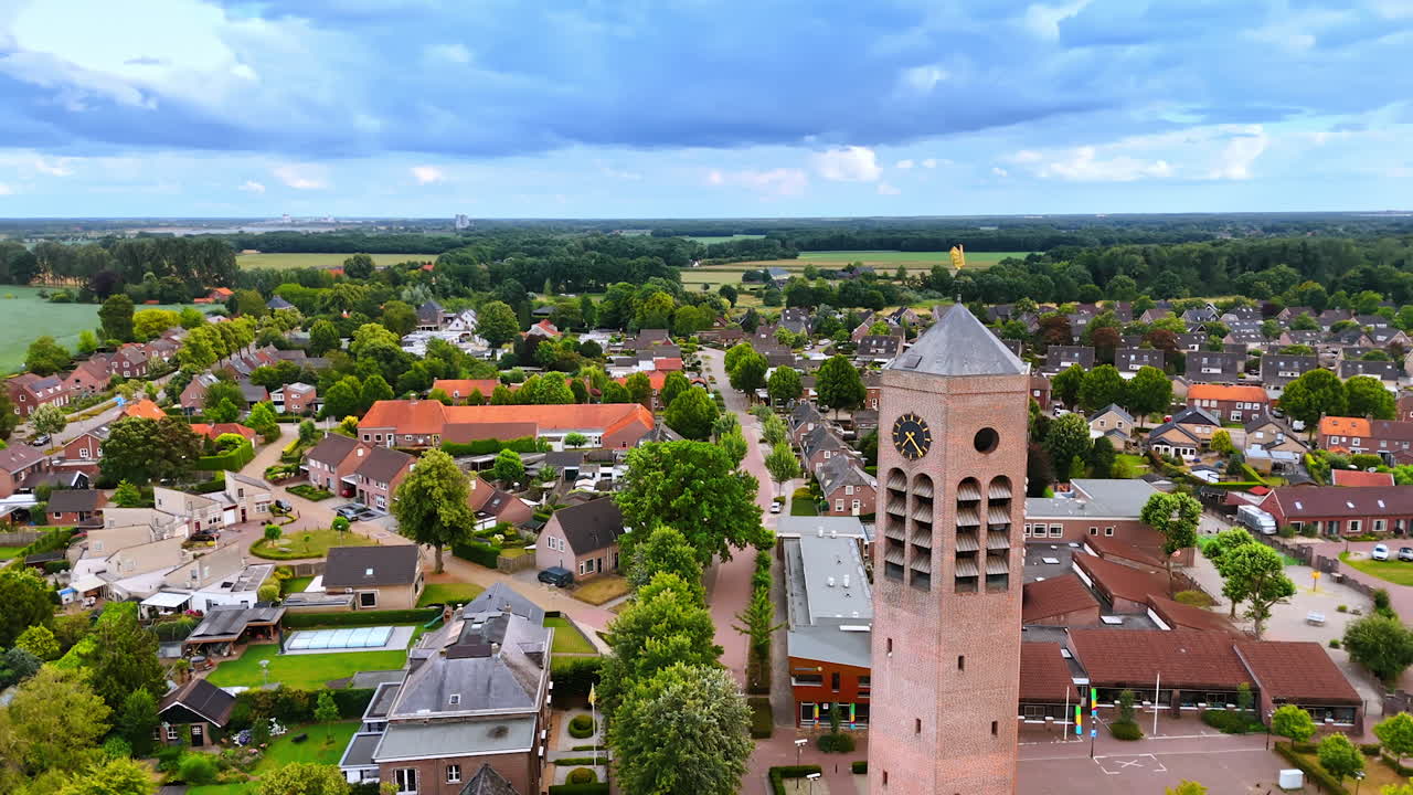 Flight around the tower with clock of Saint Lawrence Church. Picturesque scenery of residential area in Vierlingsbeek, Netherlands