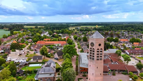flight around the tower with clock of saint lawrence church. picturesque scenery of residential area in vierlingsbeek, netherlands