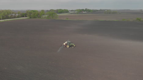 aerial drone shot day of a tractor spraying on a field