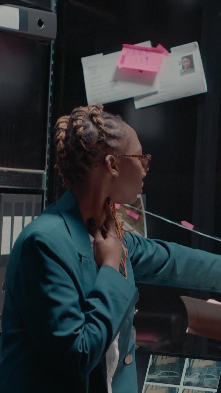 Vertical video: Detective partners analyzing criminal records in office,