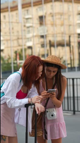 two young women looking at their phones while travelling