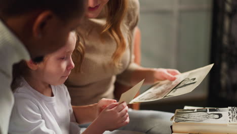 mother shows vintage photos to daughter and friend at home