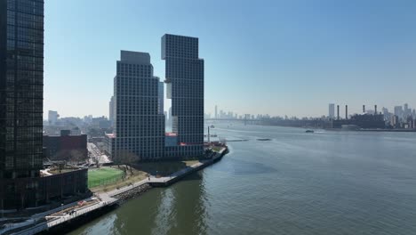 An-aerial-view-of-Newtown-Creek-with-new-high-rise-apartment-buildings-in-Brooklyn,-NY-in-the-background-on-a-sunny-day