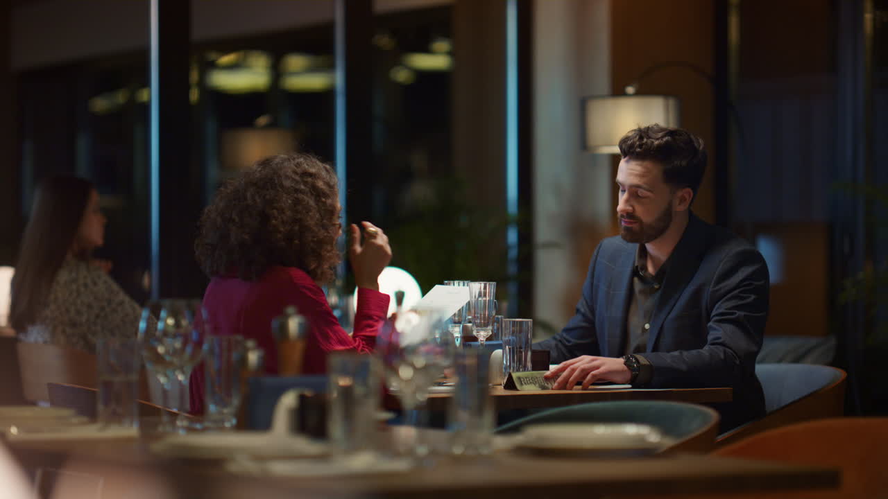 Par af forskellig etnicitet på date ved restaurantbord. Kærester vælger mad fra menuen på café