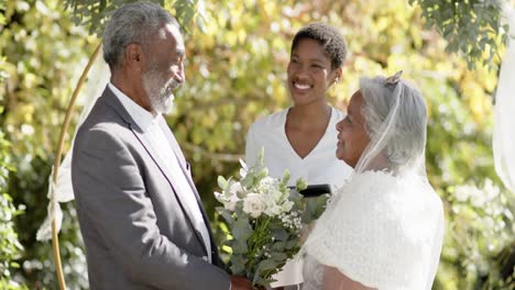 Afroamerikanische-Frau,-Die-Die-Hochzeitszeremonie-Eines-älteren-Birazialen-Paares-Im-Garten-Leitet,-Zeitlupe